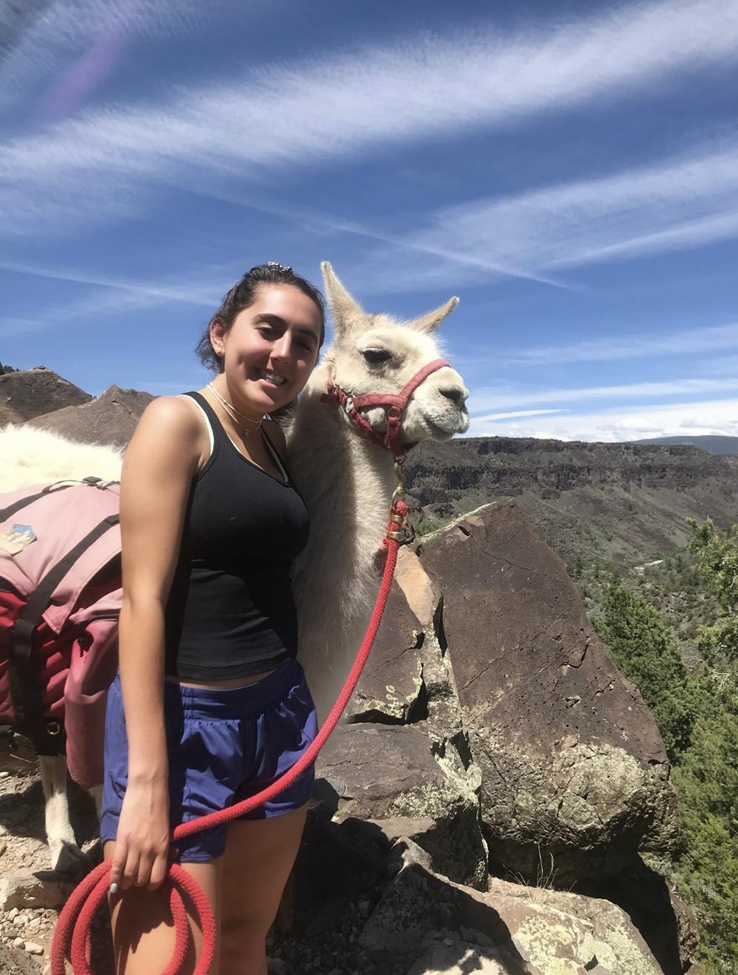 SMU-in-Taos student Aman Sergeant poses with a llama among the rocks in 新墨西哥